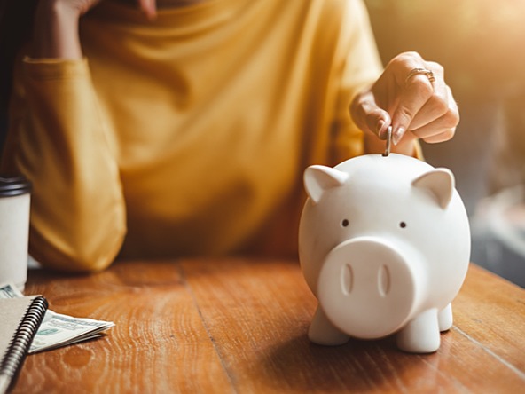 Woman puts a coin into a piggy bank